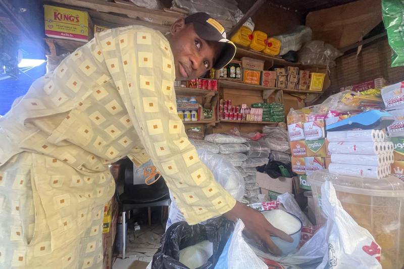 Abba Usman sells granulated sugar at his shop inside a market in Abuja, Nigeria. The same 110-pound bag of sugar that Usman bought a week ago for $66 now costs $81. As prices rise, his customers are dwindling.