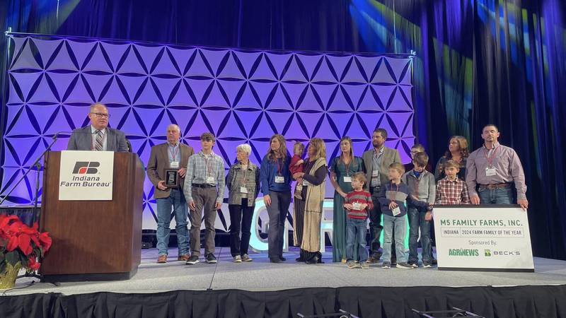 AgriNews Editor James Henry (from left) presents the 2024 Indiana Farm Family of the Year award to the Muegge family: Bruce, Kade, Mary, Cari, Sadie, Linda, Jordan, Rhett, Chris, Judd, Krue, Beau, Karver, Carli and John.