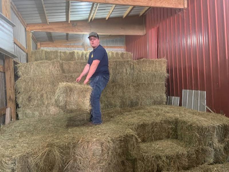 Justin Myers moves bales of hay on his farm. The FFA member also makes round bales that he sells to local customers or feeds to his livestock.