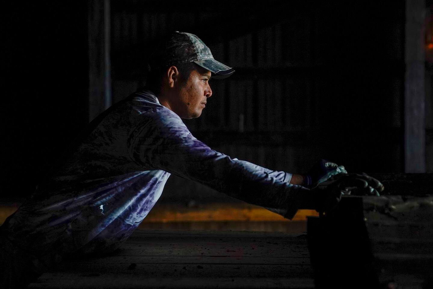Fredy Osorio, a contract worker from Veracruz, Mexico, loads pieces of sheet metal onto a trailer at a farm in Crofton, Kentucky.