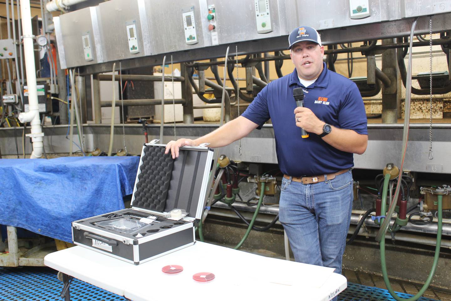 Derek Nolan explains some of the milk quality projects at the University of Illinois dairy farm while standing in the pit of the double 12 parallel milking parlor. The culture plates will give the researchers information about bacteria to help guide them on treatment decisions for cows.