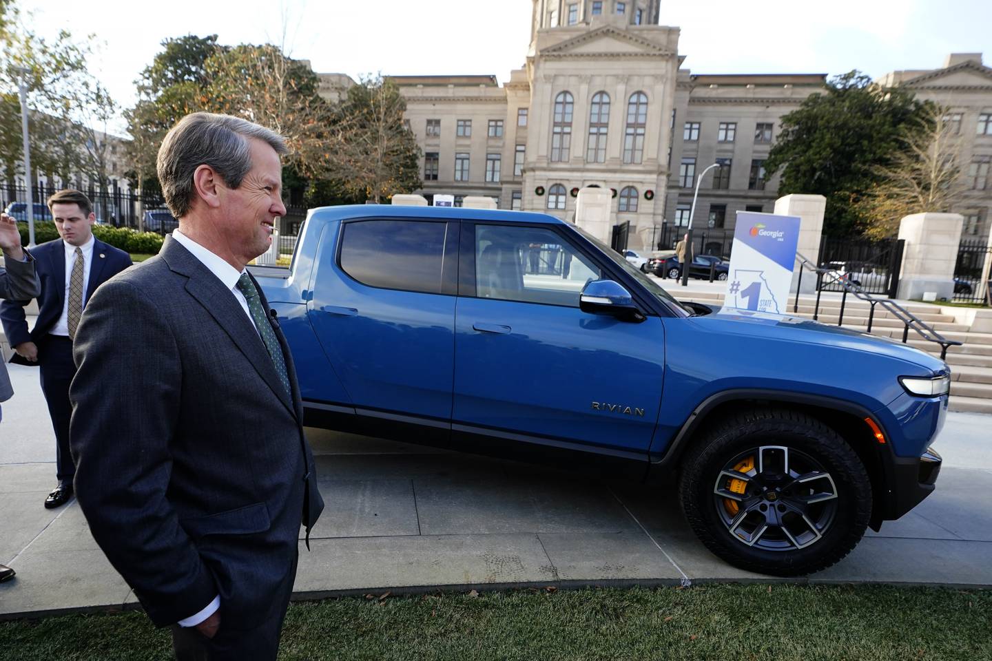 Georgia Gov. Brian Kemp smiles as he stands next to a Rivian electric truck during a ceremony in December 2021 to announce that the electric truck maker plans to build a $5 billion battery and assembly plant east of Atlanta projected to employ 7,500 workers.