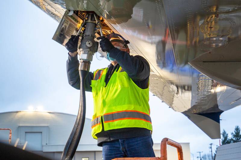 An aviation maintenance technician loads sustainable aviation fuel into a Boeing ecoDemonstrator plane.