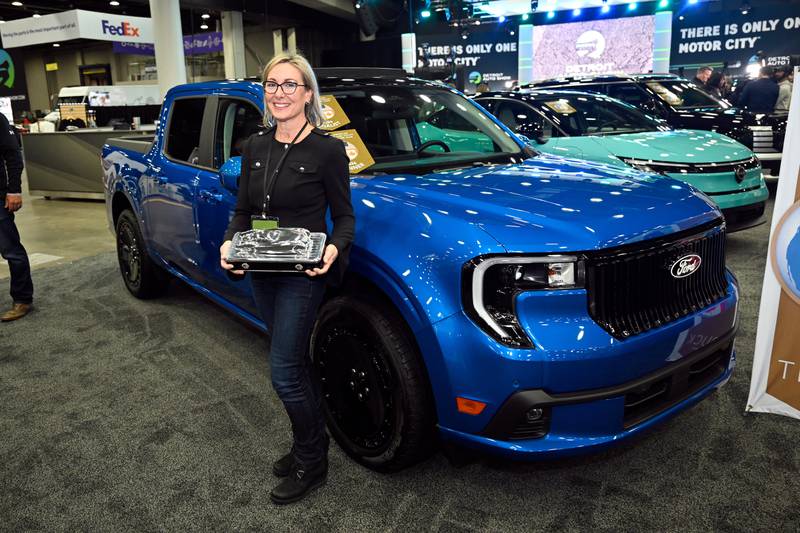 Ford Motor Company Vehicle Programs Director Pamela Wylie holds the North American Truck of the Year award in front of the Ford Maverick Lobo in Detroit.