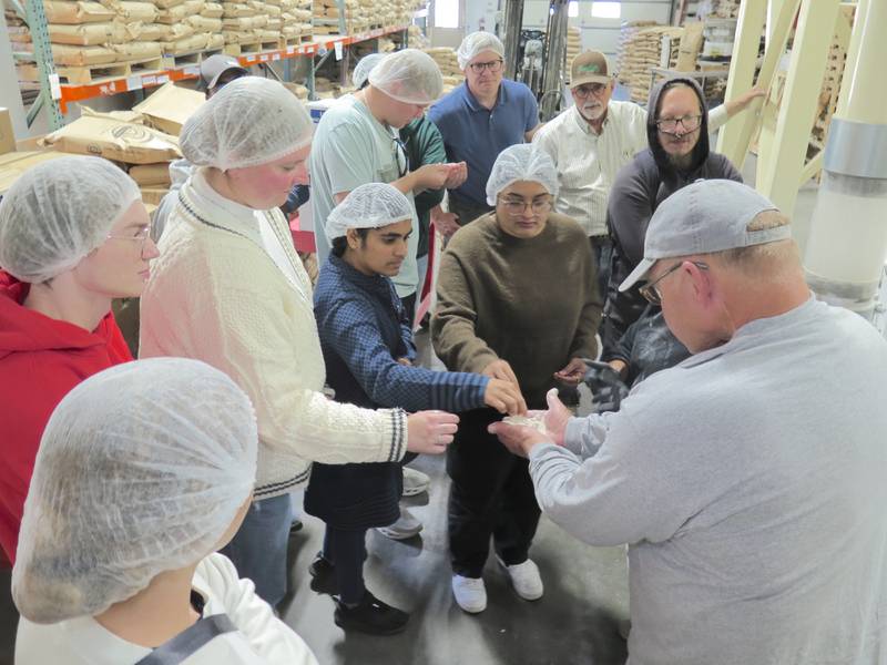 Harold Wilken, who co-owns Janie’s Farm and Janie’s Mill with his son, Ross, show Illinois State University organics class students the finished flour that went through the milling system. Corn, soybeans, wheat, rye, oats, buckwheat and other grains are grown on the farm, and those grains move on to the milling process.