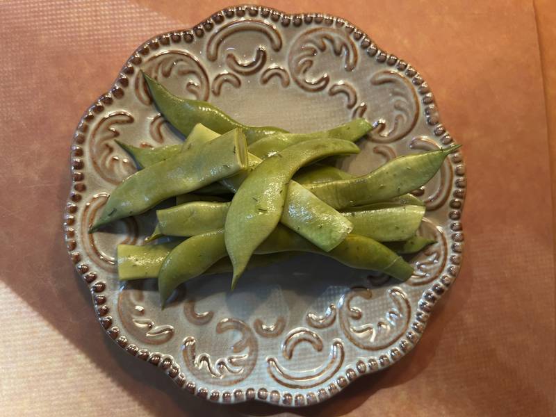 Pickled green beans are served on a decorative plate.