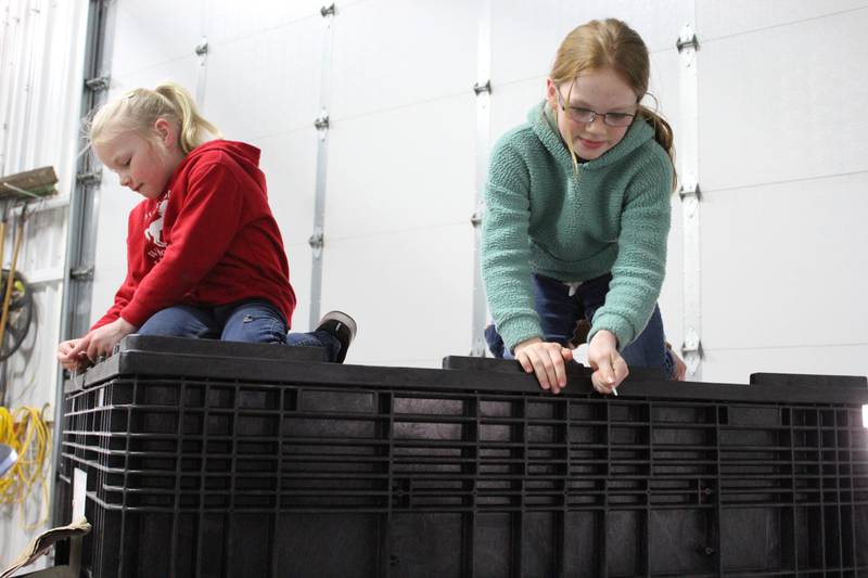 Adalynn (left) and Emilie Rahn use zip ties to secure the lid of a seed box in the seed shed at the northern Illinois farm. The kids assist their mom, Kellie, a Pioneer sales representative, with a variety of jobs as they prepare for the planting season.