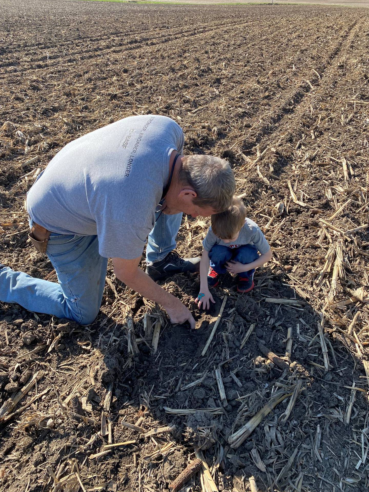 “Grandpa sharing knowledge” — Jennifer Koehler: “Grandpa checking soybean seed depth with grandson, passing on his knowledge.”
