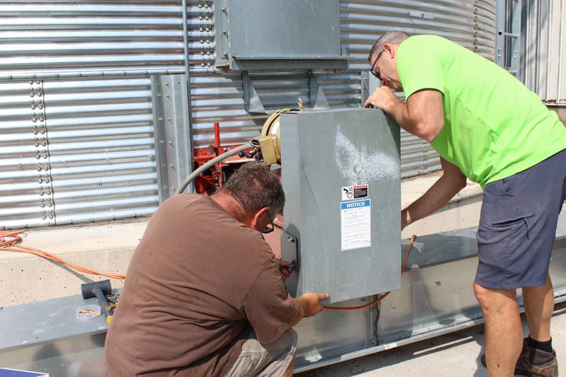 Chris Gould (right) and Ron Bychowski, the key maintenance guy for Gould Farms, re-install a cover on the grain handling system in preparation for the upcoming harvest season. Along with maintenance on the grain system, the team at the Kane County farm in northern Illinois are also completing machinery and truck maintenance.