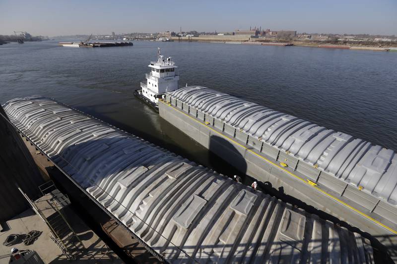 A tow switching barges pulls an empty barge alongside one filled with soybeans at an Archer Daniels Midland grain terminal along the Mississippi River in Sauget in southwestern Illinois.