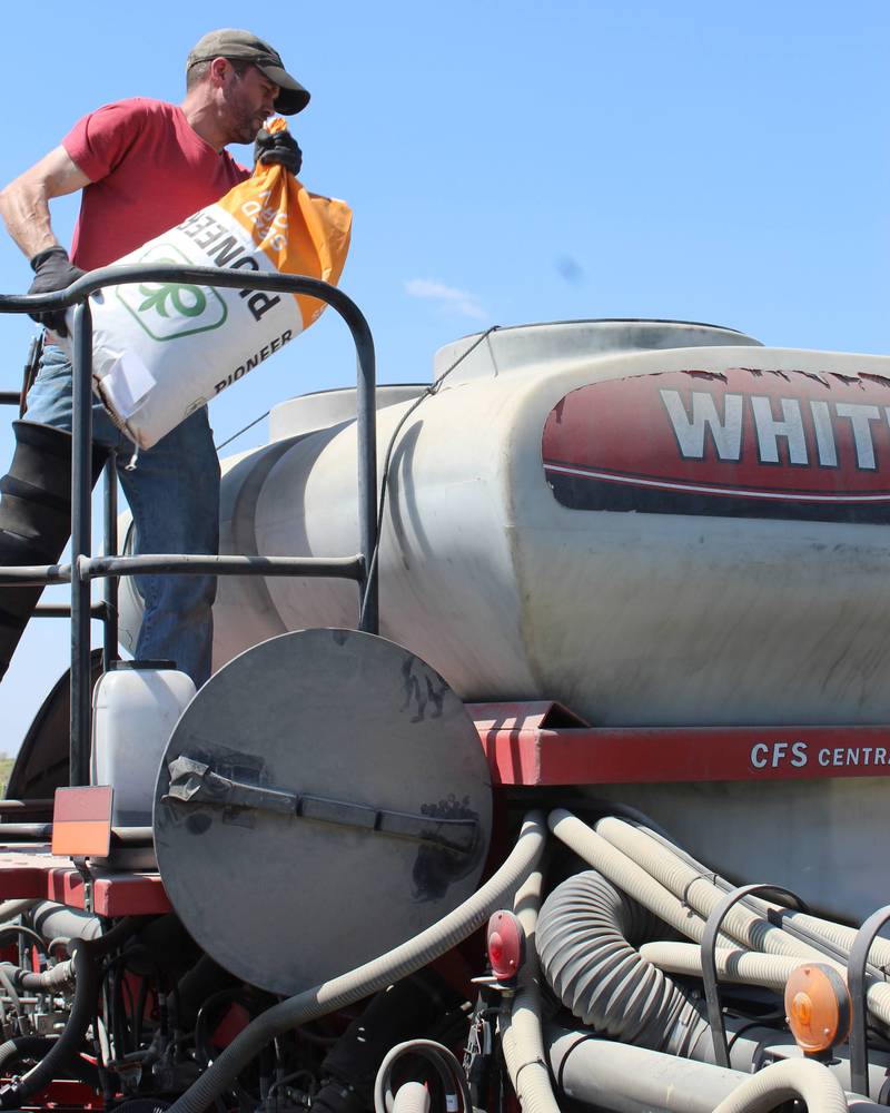 Chad Bell dumps seed into his planter to plant his first field of corn for the year. This was the second day of planting at Bell Family Farms. A soybean field was started the previous day, and his dad, Greg, operates the soybean planter so that both crops can be planted at the same time.