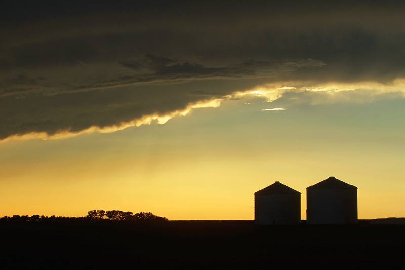 Grain bins are silhouetted against approaching storm clouds in Pleasant Plains, Illinois.