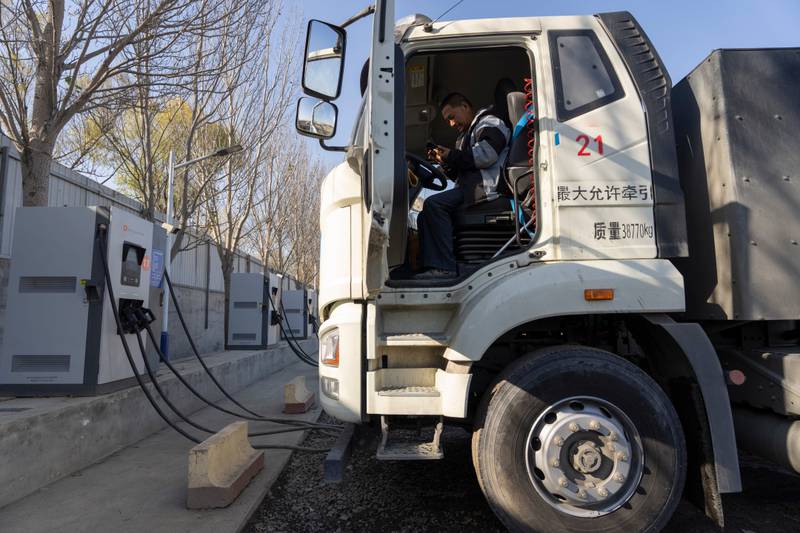 A driver sits in his electric truck at a charging station on the outskirts of Beijing.