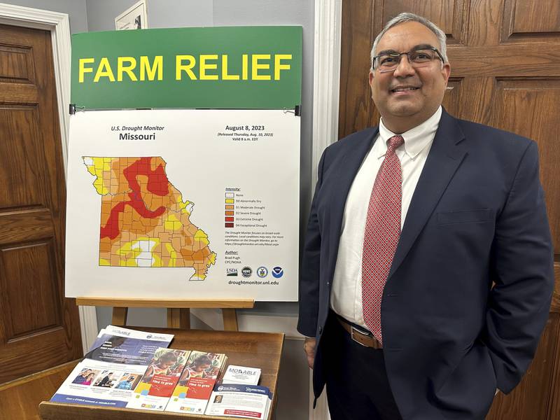 Missouri Treasurer Vivek Malek stands near a poster detailing drought conditions and state aid programs at his Capitol office in Jefferson City, Missouri. Agricultural entities are among several categories of businesses that can receive low-interest loans backed by deposits of state funds made by the treasurer’s office. Participation in such programs has grown in various states.
