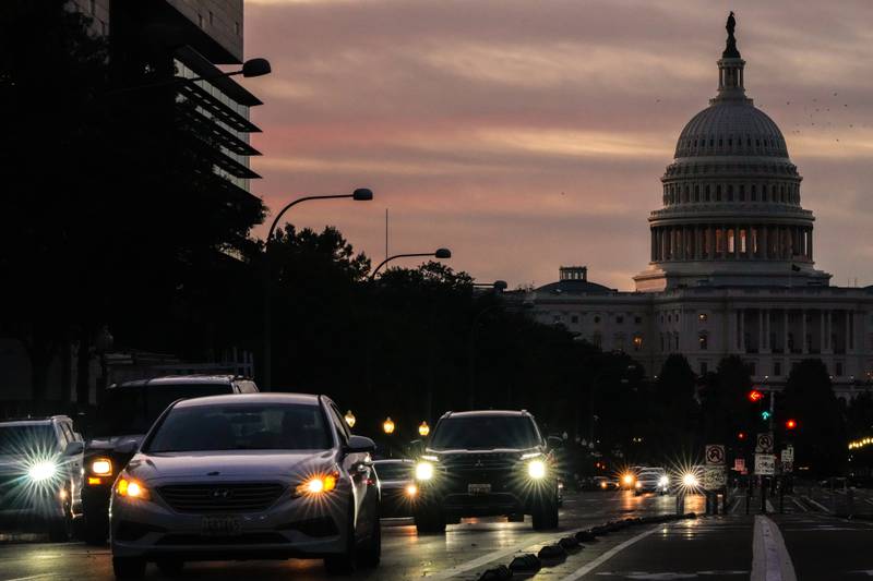 Vehicles drive along Pennsylvania Avenue during rush hour traffic at sunrise in Washington, with the U.S. Capitol in the background.