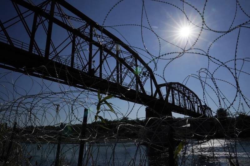 The Union Pacific International Railroad Bridge is seen behind concertina wire in Eagle Pass, Texas. The federal government on Dec. 22 reopened railroad crossings in two Texas border towns, including Eagle Pass, days after the shuttering of rail operations there disrupted trade and caused outrage.