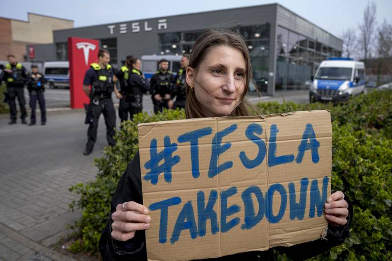 A protester holds a placard during a Tesla Takedown Global Day protest in front of a Tesla dealership in Berlin.