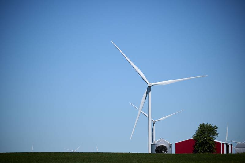 Wind turbines stand on farmland with a large red barn in rural Gibson City in east-central Illinois.