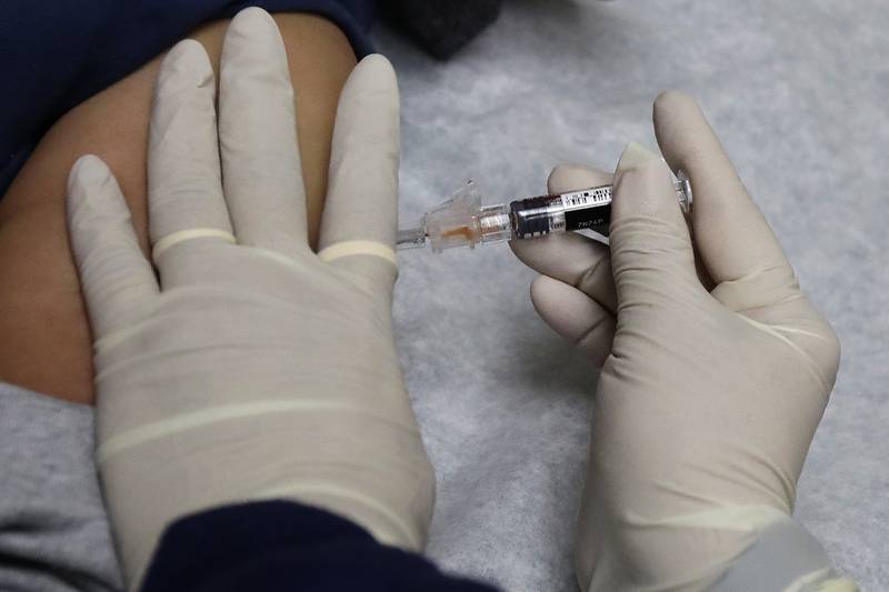 A medical assistant at a community health center gives a patient a flu shot.