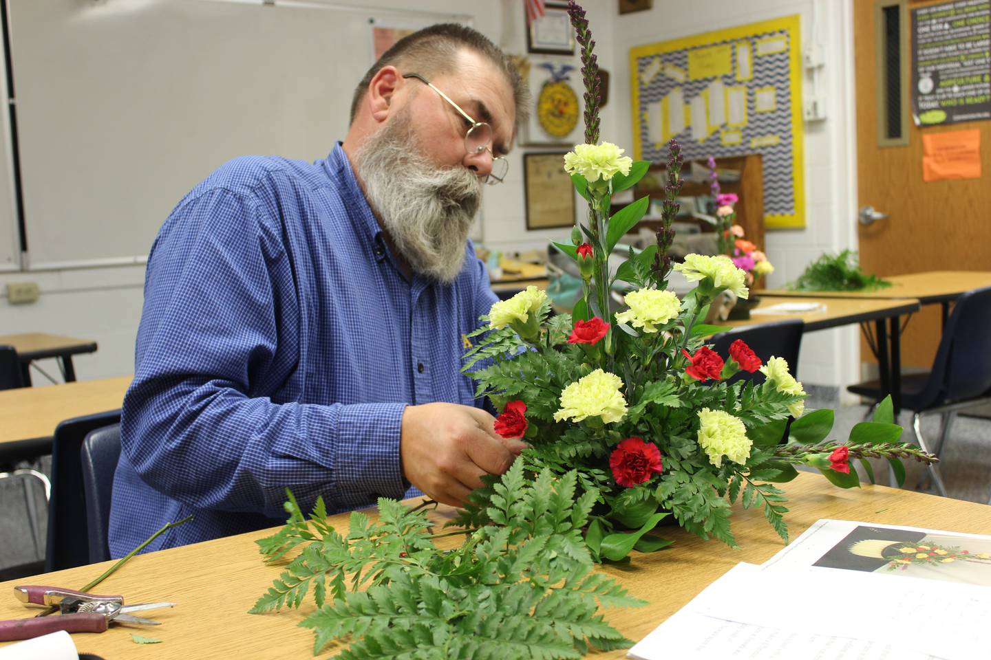 Joe Steffen demonstrates how to complete a flower arrangement for students in preparation for a FFA horticulture contest. For this event, students are challenged to complete an arrangement that looks like a provided picture.