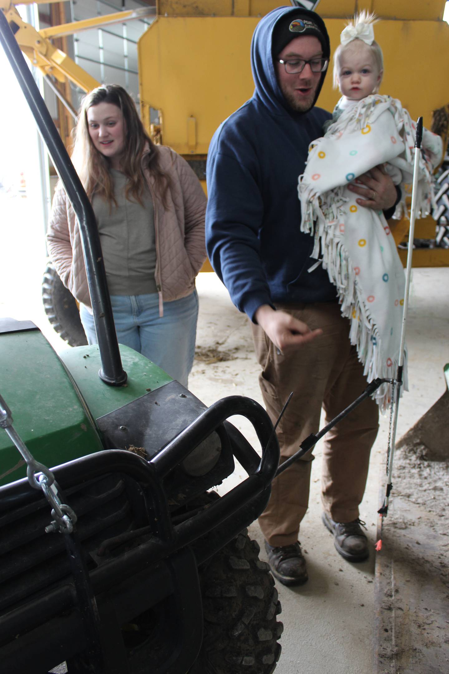 Mitchel Rahn, holding his daughter, Emmerson, explains how he uses the Gator with a GPS receiver to map the boundaries of the fields, while his wife, Samantha looks on.
