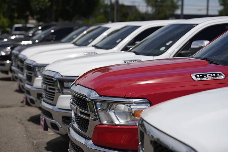 Pickup trucks sit in a long row at a Ram dealership.