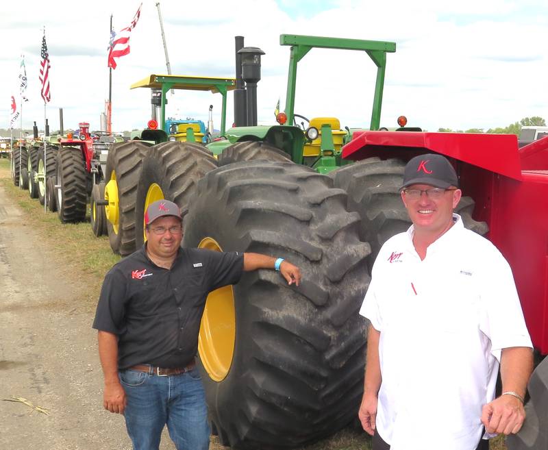Alex Kerr (left) and Matt McCaskill stand next to tractors from the 1960s through the 1980s featured at Kerr Auction’s exhibit during the Half Century of Progress.