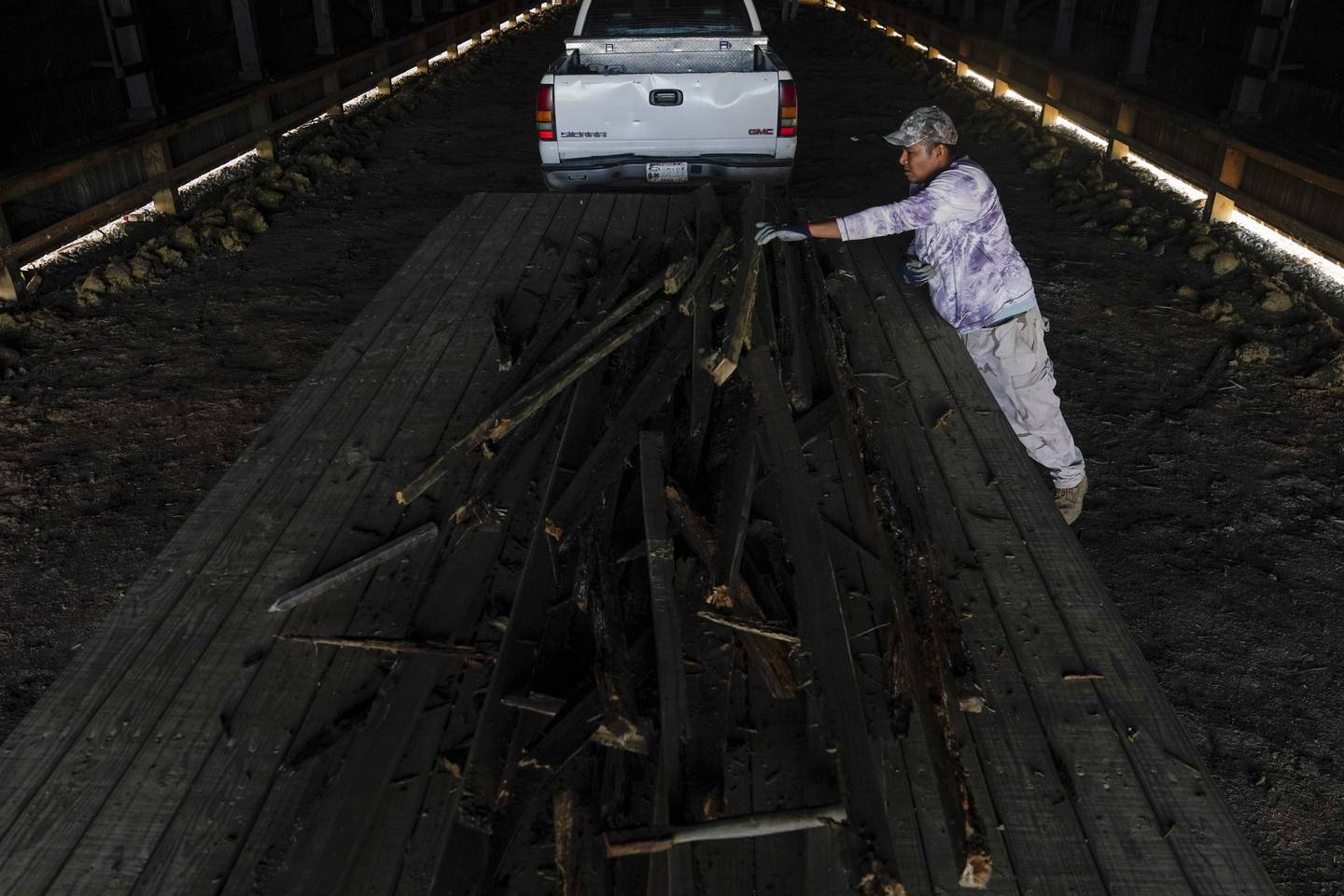 Fredy Osorio, a contract worker from Veracruz, Mexico, tosses wood scraps onto a trailer at a farm in Crofton, Kentucky.