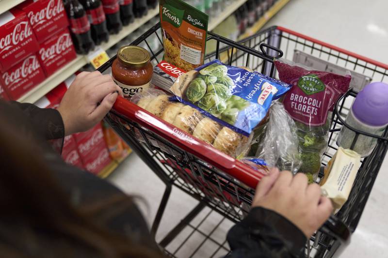 A food shopper pushes a cart of groceries at a supermarket in Bellflower, California.