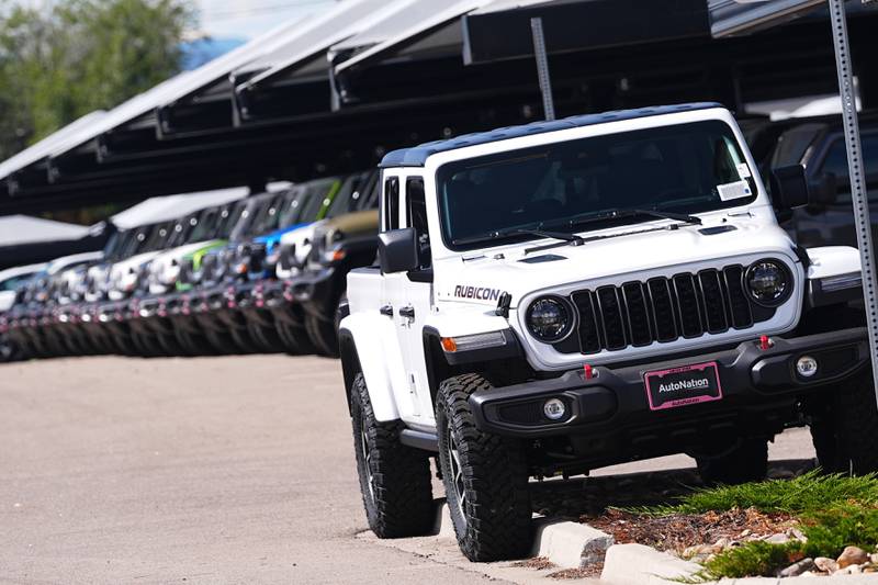 Unsold 2025 Gladiator pickup trucks sit on display outside a Jeep dealership.