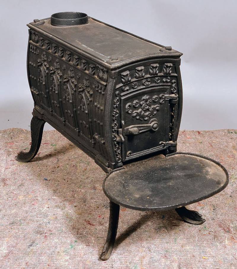 This cast-iron wood stove kept a 19th-century room warm. Its embossed designs, especially the rows of pointed arches on its sides, were meant to evoke medieval architecture.