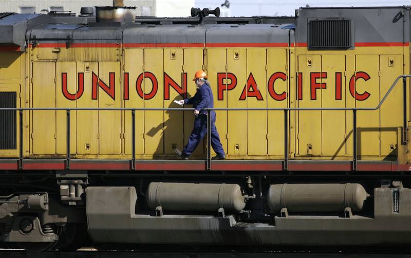 A maintenance worker walks past the company logo on the side of a locomotive in the Union Pacific Railroad fueling yard in north Denver.