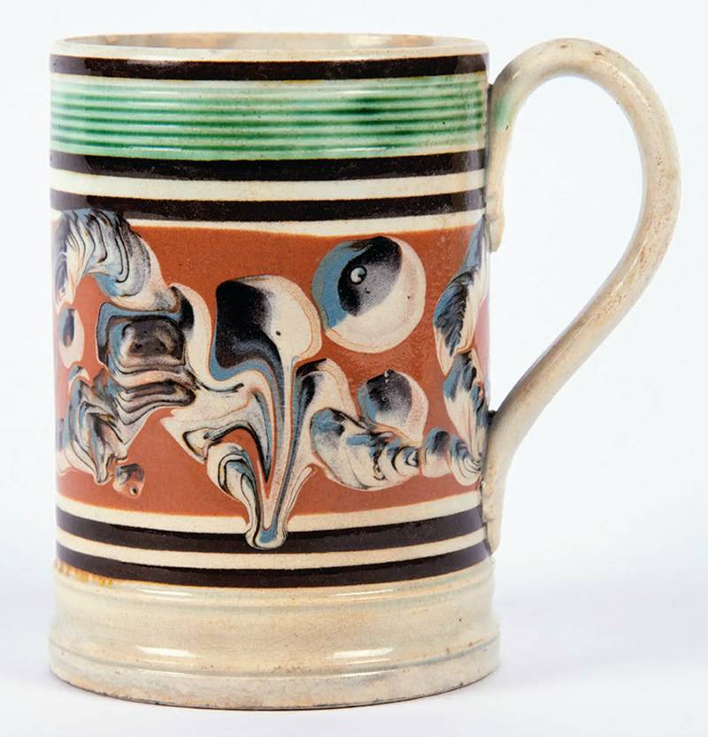 Antique mocha ware caught collectors’ attention in the mid-20th century. Like many mocha pieces, this colorful mug is decorated with several patterns.