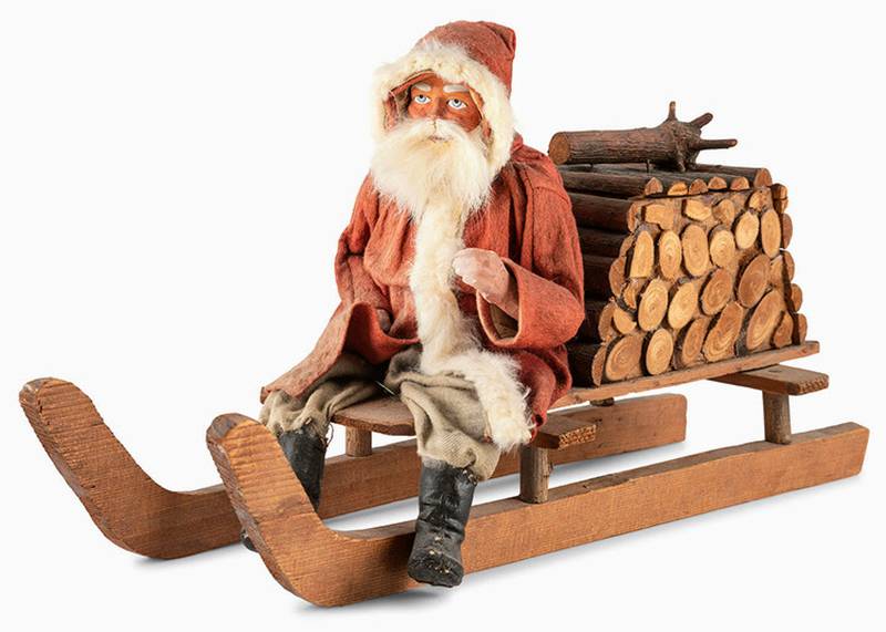 Leave it to Santa Claus to fill a bundle of firewood with candy. This papier-mâché figure of Santa on a sled is a candy container.