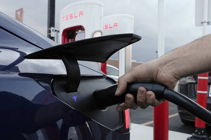 A motorist charges his electric vehicle at a Tesla Supercharger station in Detroit.