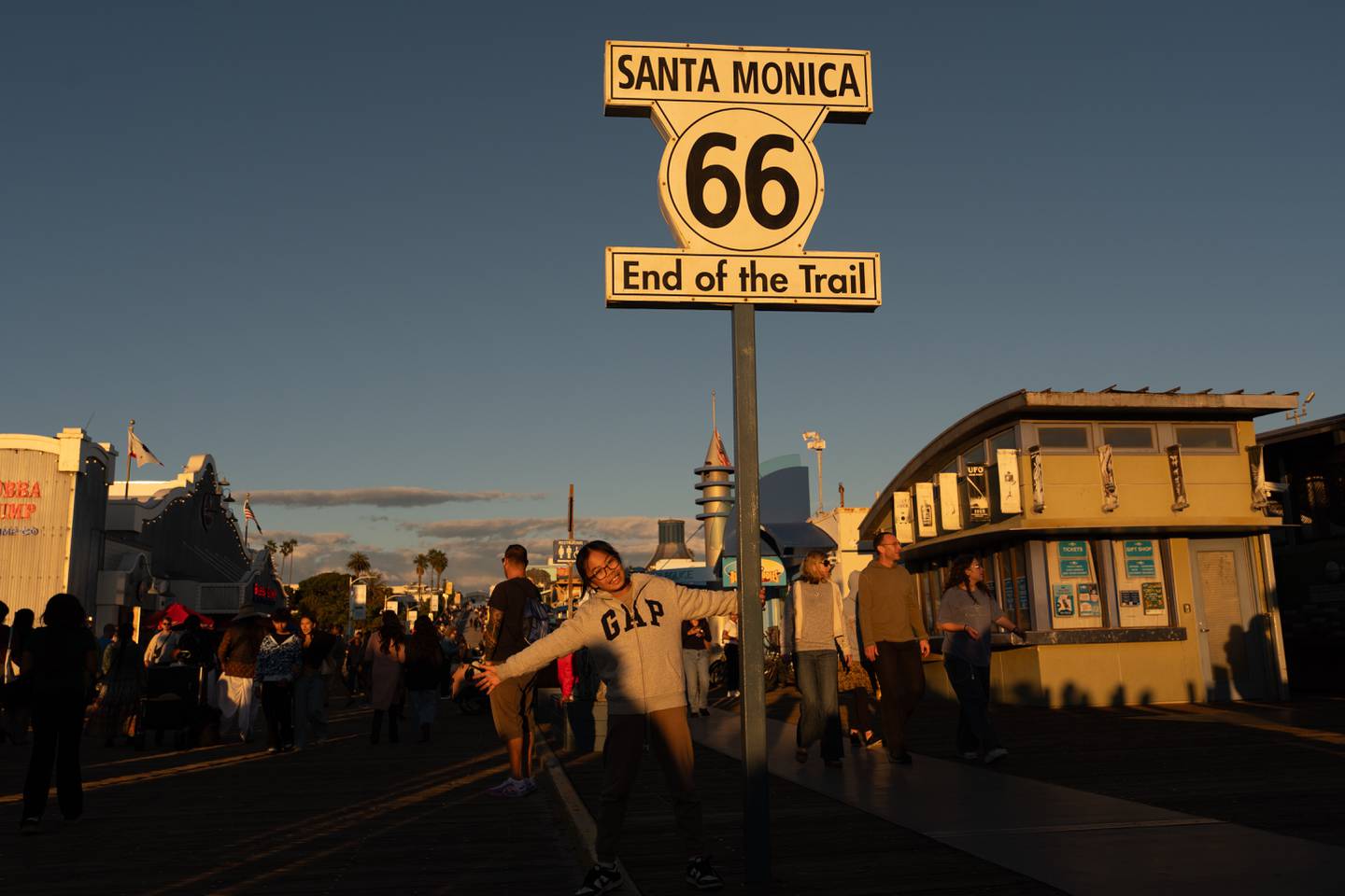 A visitor poses for photos with the "End of the Trail" Route 66 sign on the Santa Monica Pier in Santa Monica, California.