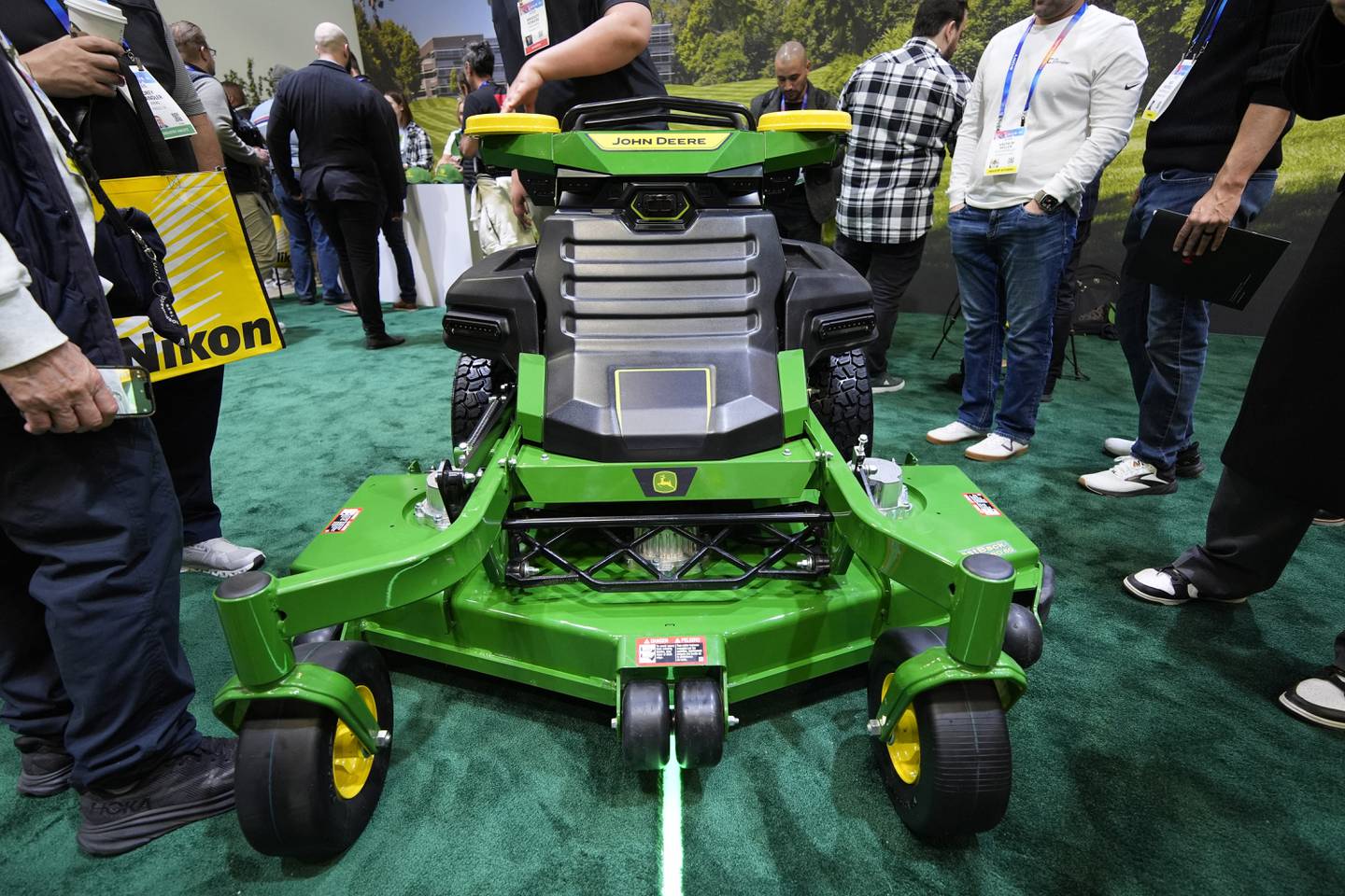 People view an autonomous lawn mower at the John Deere booth during the CES tech show in Las Vegas.