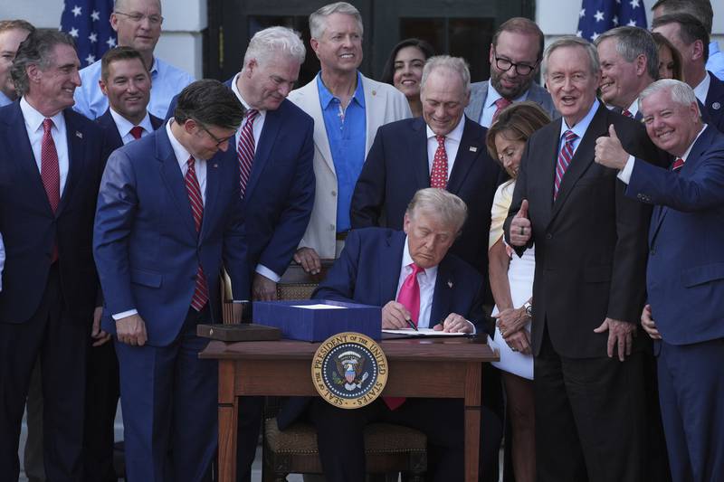 President Donald Trump signs his signature bill of tax breaks and spending cuts at the White House on July 4 in Washington, surrounded by members of Congress.