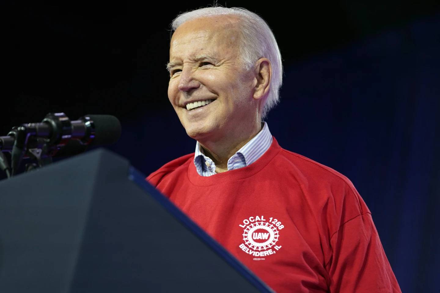 President Joe Biden puts on a UAW Local 1268 shirt before speaking to United Auto Workers at the Community Building Complex of Boone County in Belvidere, Illinois.