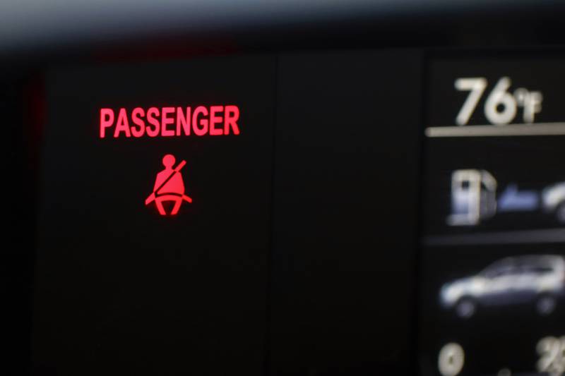A seat belt warning sign for the right front passenger seat is displayed in a vehicle.