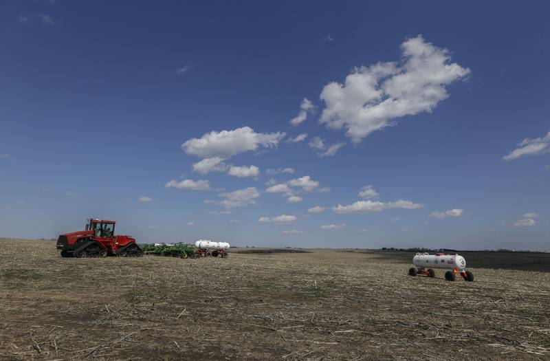 Fertilizer tanks and other farm equipment sit in a field.