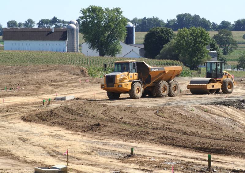 Excavation equipment sits at a new housing development adjacent to a cornfield.