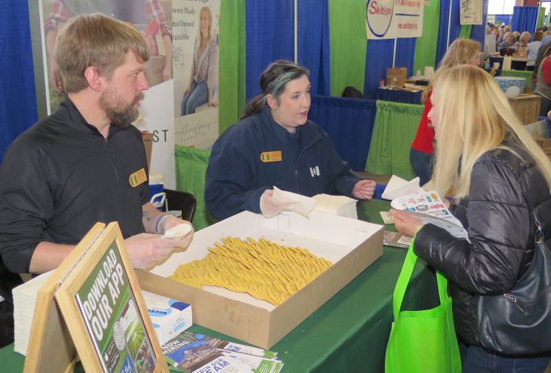 Aaron Forgas, operations manager at Niemann Harvest Market, Springfield, and Grace Beneky, bakery cook, hand out samples of a unique sugar cookie at their Illinois Product Expo booth. Beneky uses Illinois-grown sweet corn in the cookie.