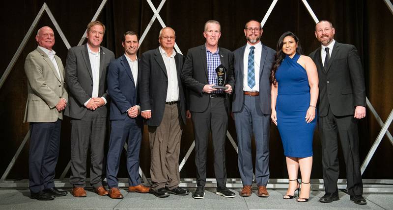 Rick Beaman (from left), Brad Suhling, Charlie Mack, Greg Helbig, Brett Sollberger, Ken Klug, Ana Guillen and James Luyben pose with the QCS Best Collaboration Award honoring Prairie Farms and Hiland Dairy.