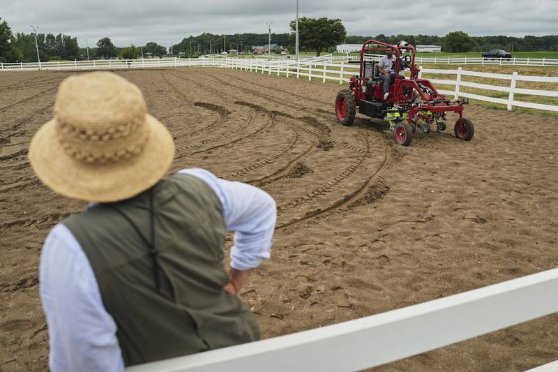 MK Bashar (right) test drives an electric tractor as Ben Phillips (left) watches during a demonstration in East Lansing in Michigan’s Lower Peninsula.