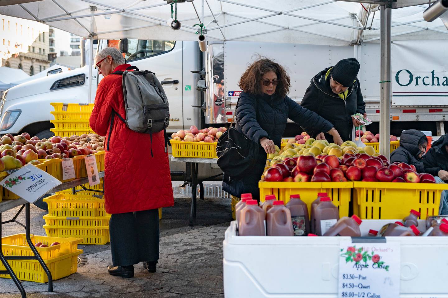 Customers browse farmers market displays.
