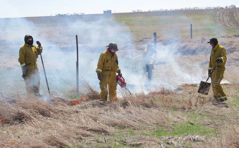 The first step in a prescribed burn is creating a ring downwind around the outside of the wetland area to trap the fire within that unit, then moving the fire into the wetland. Crew members wearing protective gear use various hand tools such as shovels, fire rakes, fire brooms and swatters to control the fire. A water tank was also on standby if needed.